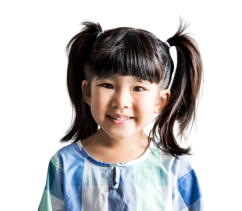 Smiling young girl with dark hair in pigtails, wearing a blue and white checkered shirt, standing against a plain white background.